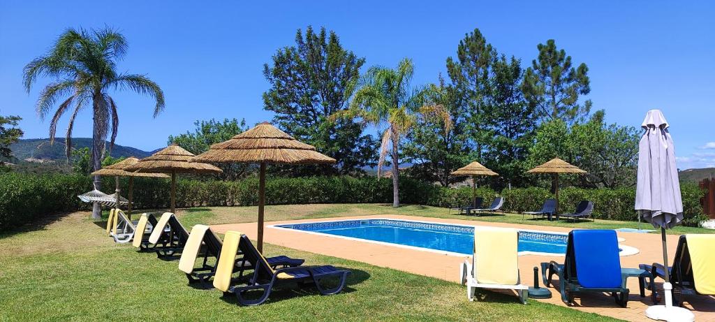 eine Gruppe von Stühlen und Sonnenschirmen neben einem Pool in der Unterkunft Nave Redonda do Cerro – Countryside & Nature in Nave Redonda