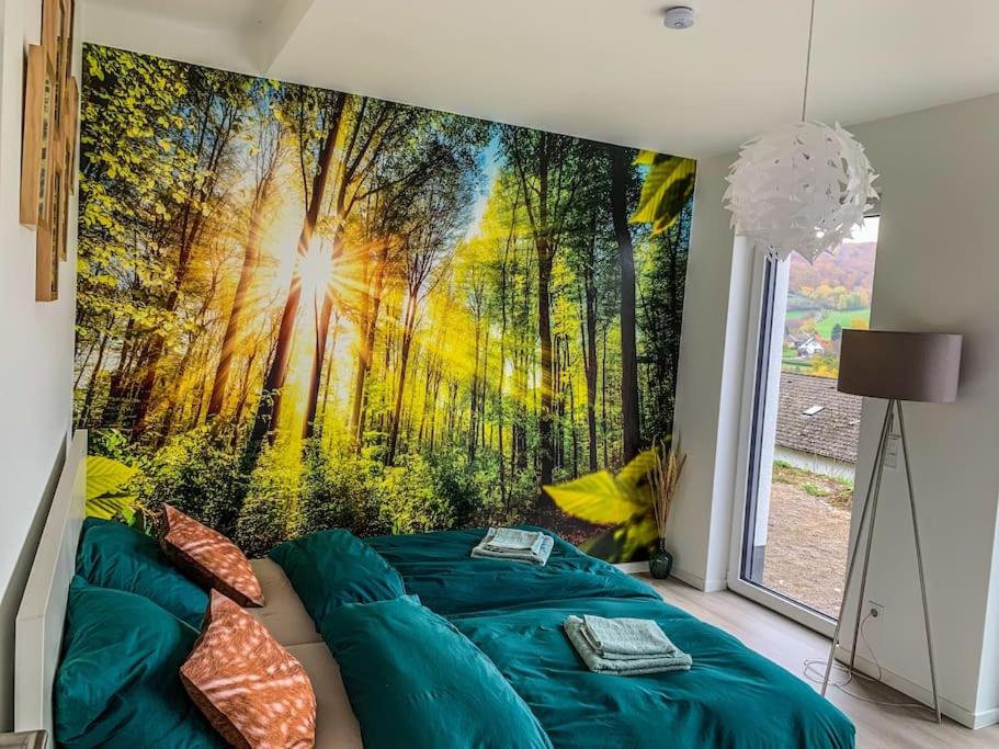 ein Schlafzimmer mit einem Bett und einem Wandbild aus dem Wald in der Unterkunft Modernes Doppelzimmer Friedewald Rhönblick in Friedewald