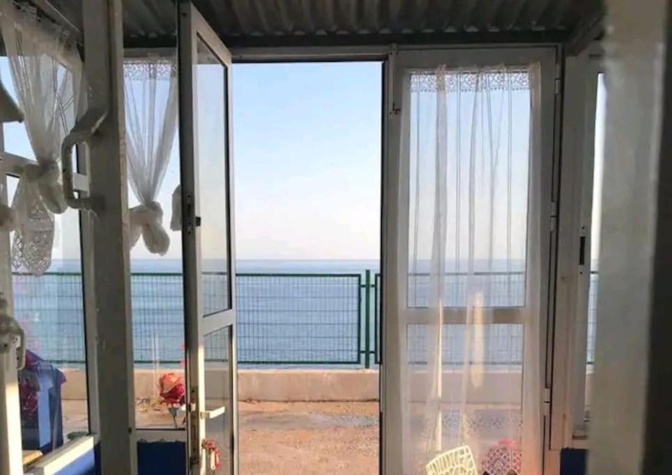 una porta aperta su un balcone con vista sull'oceano di The Beach Hut with Lazy spa ad Adra