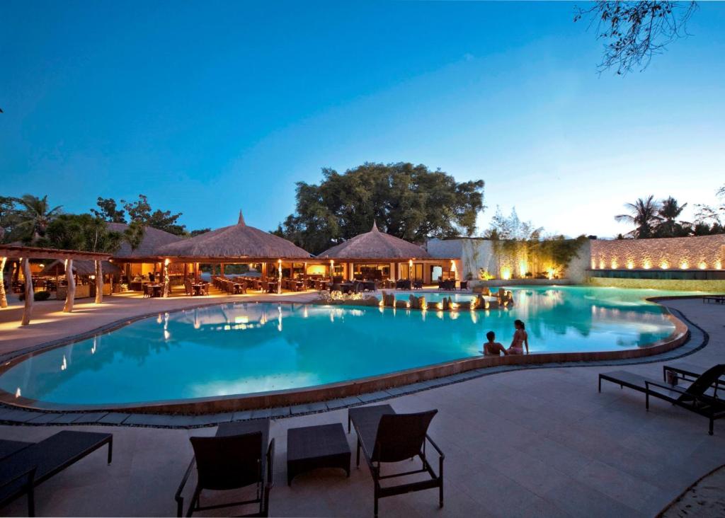 a swimming pool at night with people sitting around it at Bluewater Maribago Beach Resort in Mactan