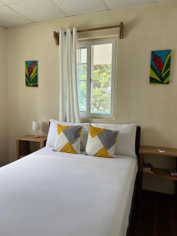 Un dormitorio con una cama blanca con almohadas y una ventana en A&K Island Apartments en Bocas Town