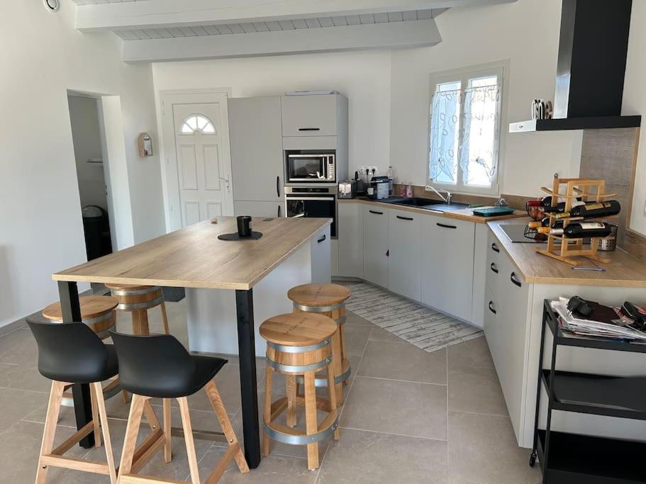 uma cozinha com uma mesa de madeira e bancos em Location du Klan des K : villa 4 étoiles 150m plage em Les Sables Vignier