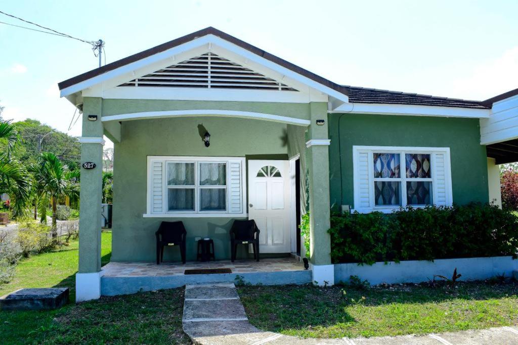 a green house with a white door and a porch at HARMONY LA VISTA in Runaway Bay