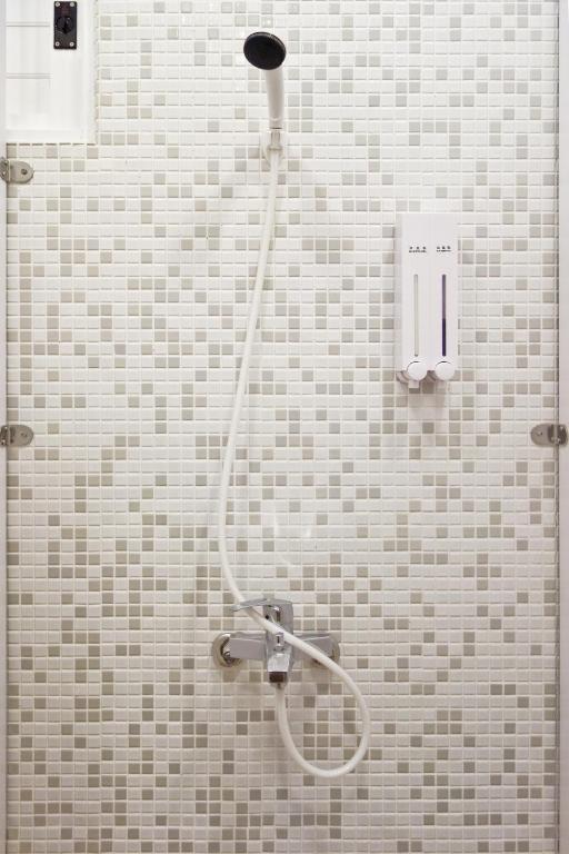a shower with a hose in a tiled bathroom at T-Life Hostel in Longjing