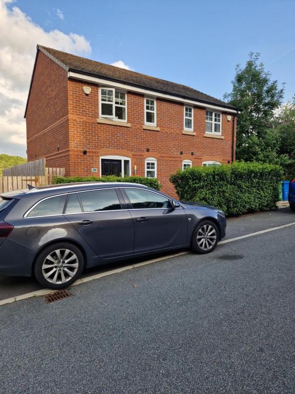 a blue car parked in front of a house at Private room in Manchester