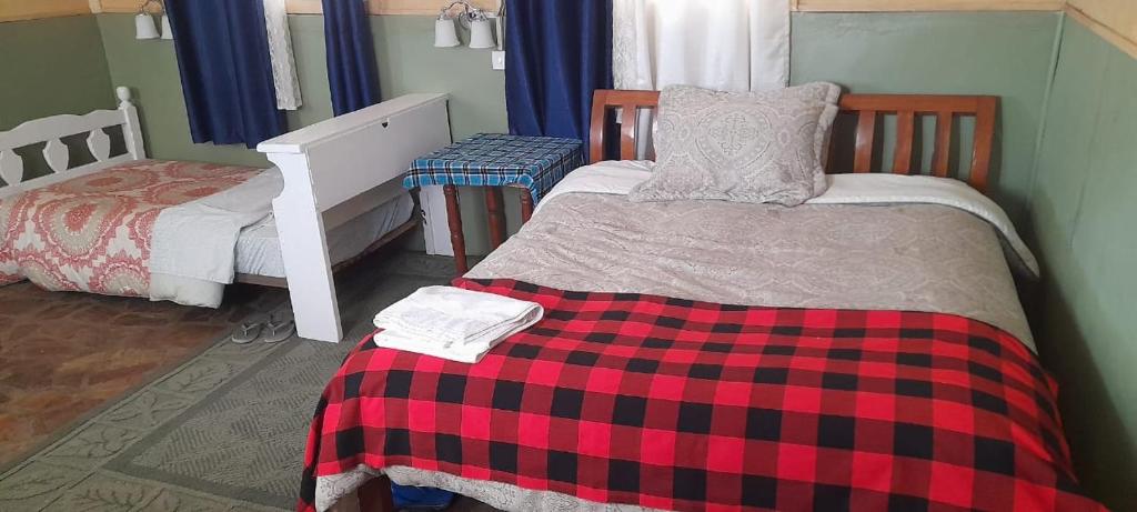 um quarto com 2 camas e um cobertor xadrez vermelho e preto em Lookout homestay em Sekenani