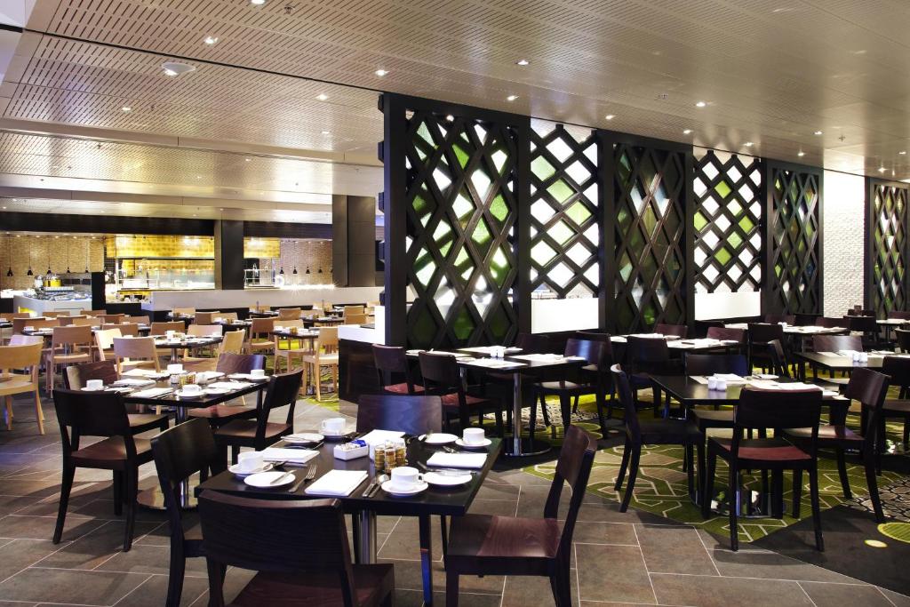 a dining room with tables and chairs in a restaurant at Crown Promenade Melbourne in Melbourne