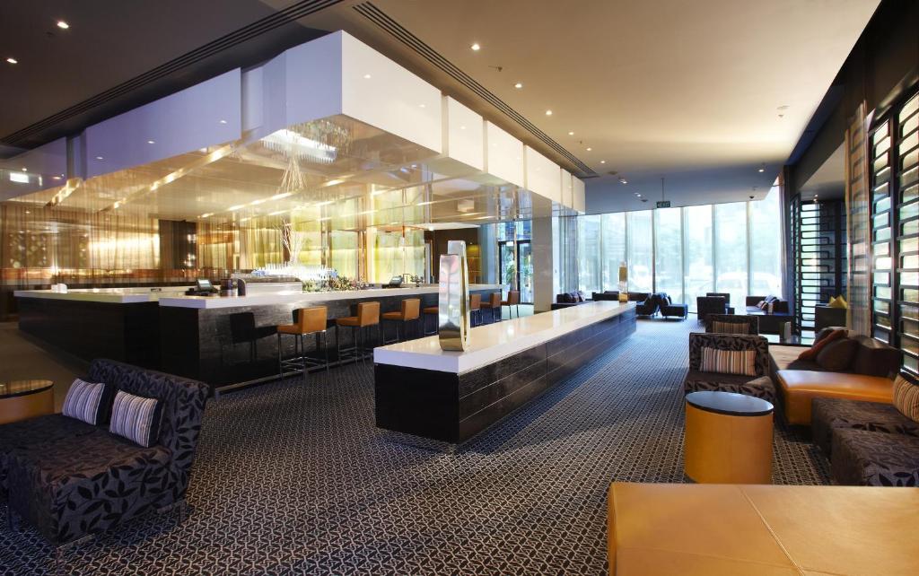 a lobby with a bar and some chairs at Crown Promenade Melbourne in Melbourne