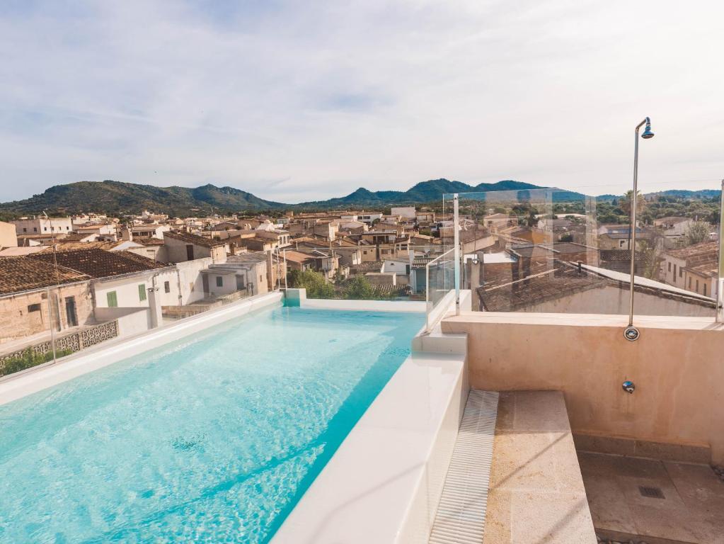 a large swimming pool with a city in the background at Hotel Boutique Can Pocovi in Sant Llorenç des Cardassar