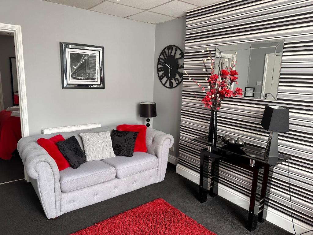 a living room with a couch and a clock on the wall at Berkswell Holiday Apartments in Blackpool