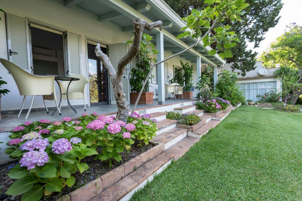 un porche delantero con flores y un árbol en Giacaranda B&B, en Castellabate