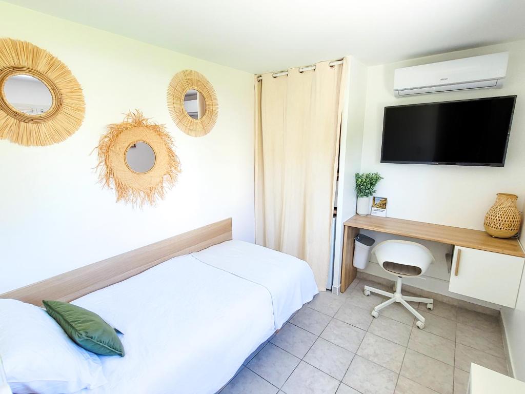 a bedroom with a bed and a desk with a tv at Chambre simple climatisée - Proche Tram & Centre in Montpellier