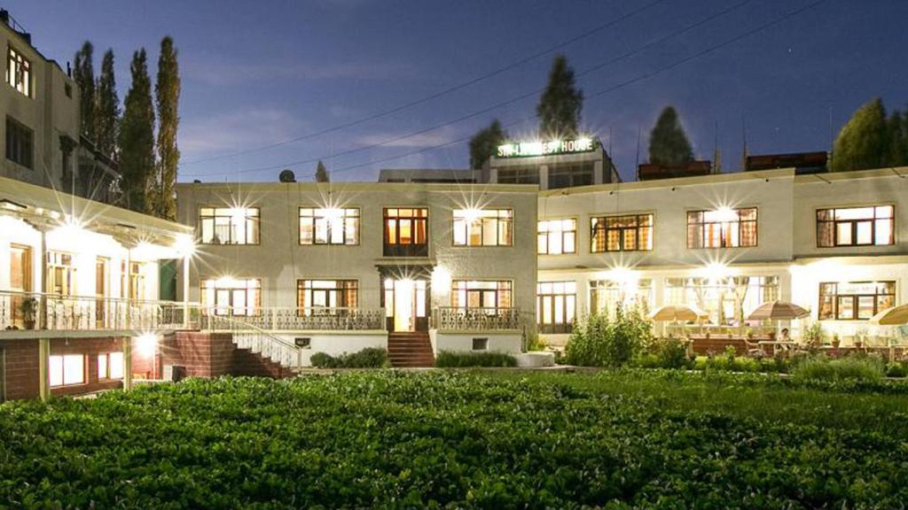 un grand bâtiment blanc avec ses lumières allumées la nuit dans l'établissement Siala Guest House, à Leh