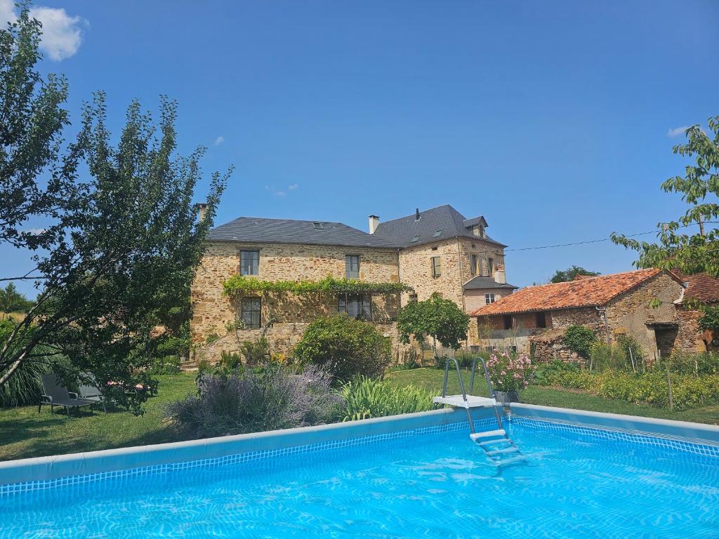 una gran casa de piedra con piscina frente a ella en Les Peyronnies, en Figeac