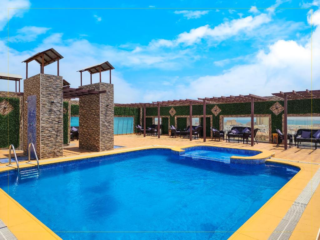 een zwembad in een resort met tafels en stoelen bij هوليداي الخليج الخبر Holiday Al Khaleej Hotel in Al Khobar