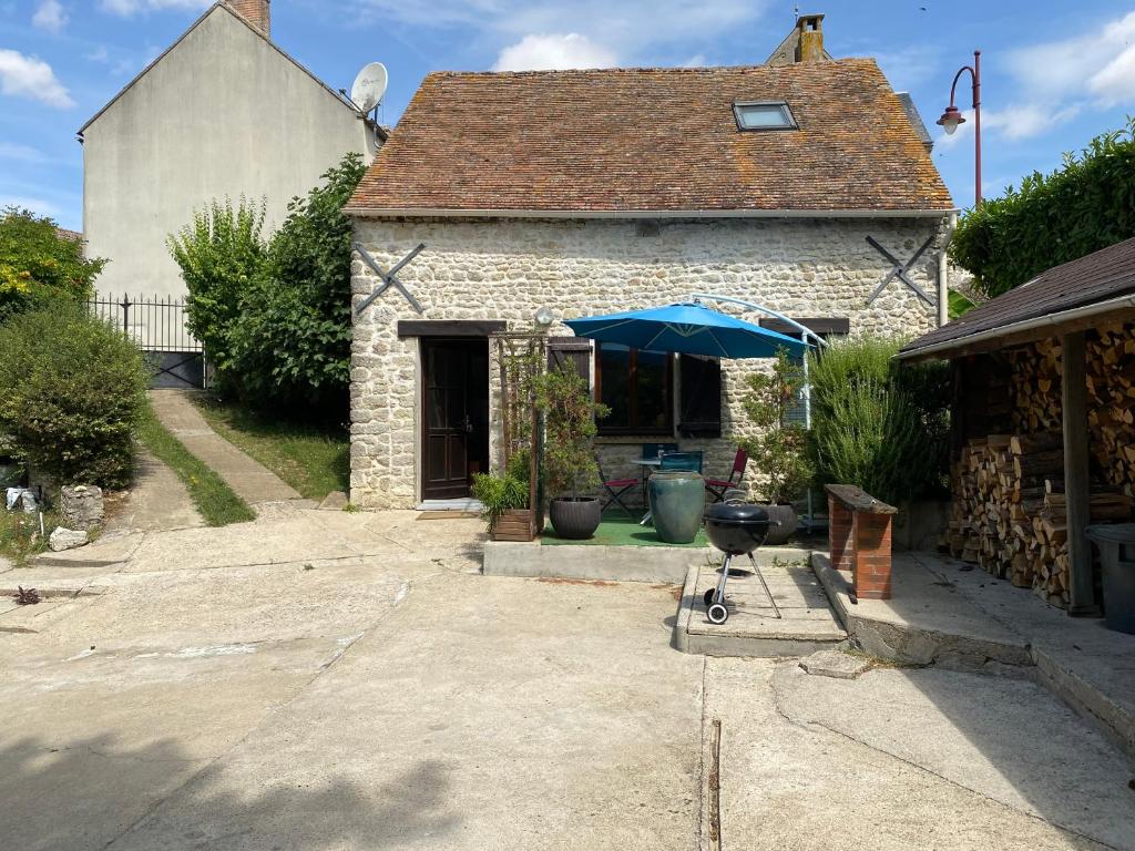una piccola casa di pietra con un ombrello blu di maison en pierre atypique sur jardin paysagé a Orveau-Bellesauve