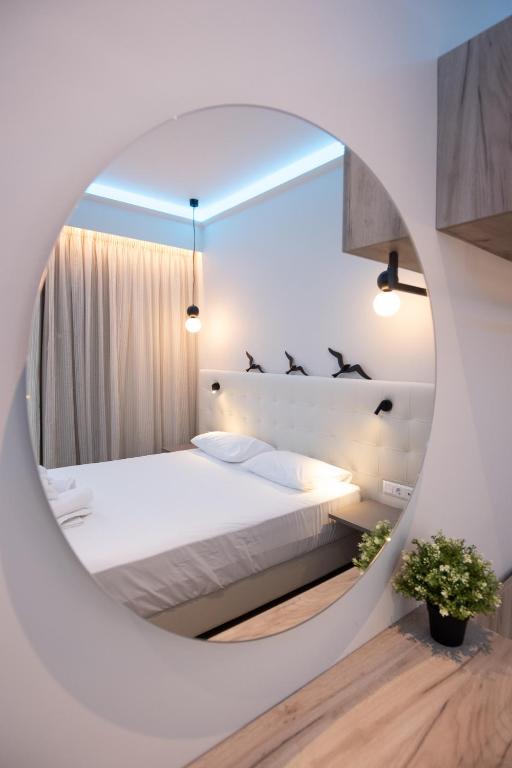 ein Schlafzimmer mit einem weißen Bett und einem runden Spiegel in der Unterkunft SEKRETO hotel in Parga