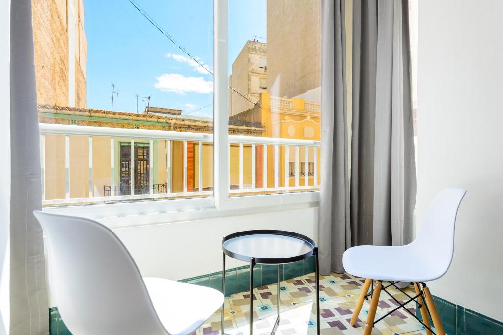 einen Balkon mit zwei weißen Stühlen und einem Fenster in der Unterkunft Bieti Castellon in Castellón de la Plana