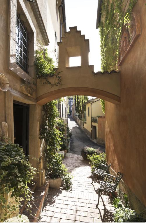 an alley with an arch in a building with benches at La Casetta di Borgo - Gli Ulivi in Lajatico