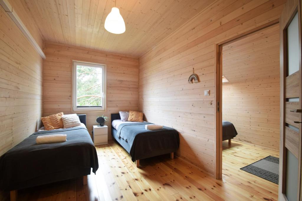 two beds in a room with wooden walls at Rafa Międzywodzie in Międzywodzie