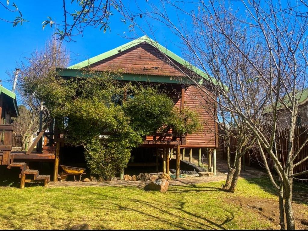 a large wooden cabin with a green roof at Cinnamon & Sage Country Cabins in Dullstroom