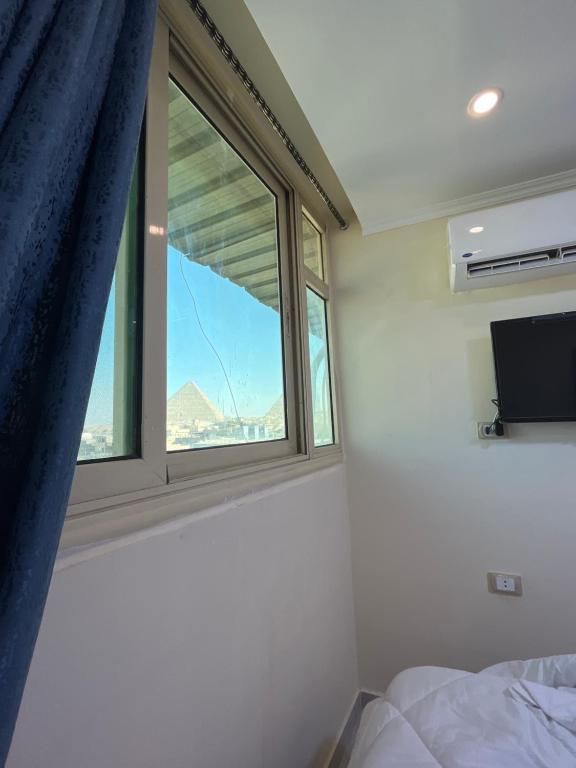 a bedroom with a window with a bed and a tv at Pyramids Pride Inn in Cairo