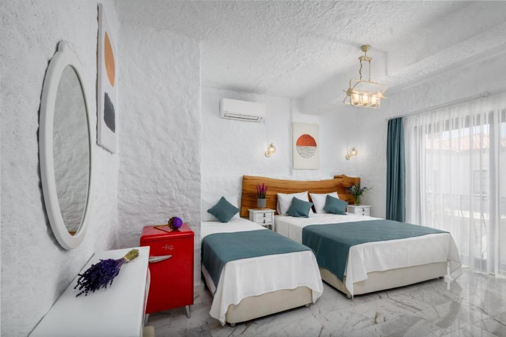 een hotelkamer met 2 bedden en een spiegel bij Fethi Baba Konağı in Izmir
