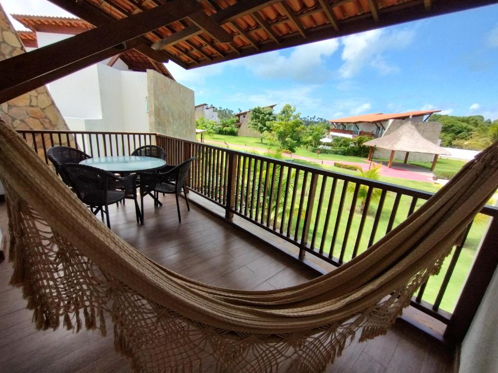 un balcón con hamaca, mesa y sillas en Apartamento 1PP B100 - Condomínio Club Meridional - Praia dos Carneiros - Pernambuco, en Praia dos Carneiros