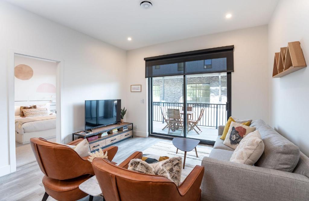 a living room with a couch and chairs and a tv at Summit Place - Condo With Mountain Views in Revelstoke
