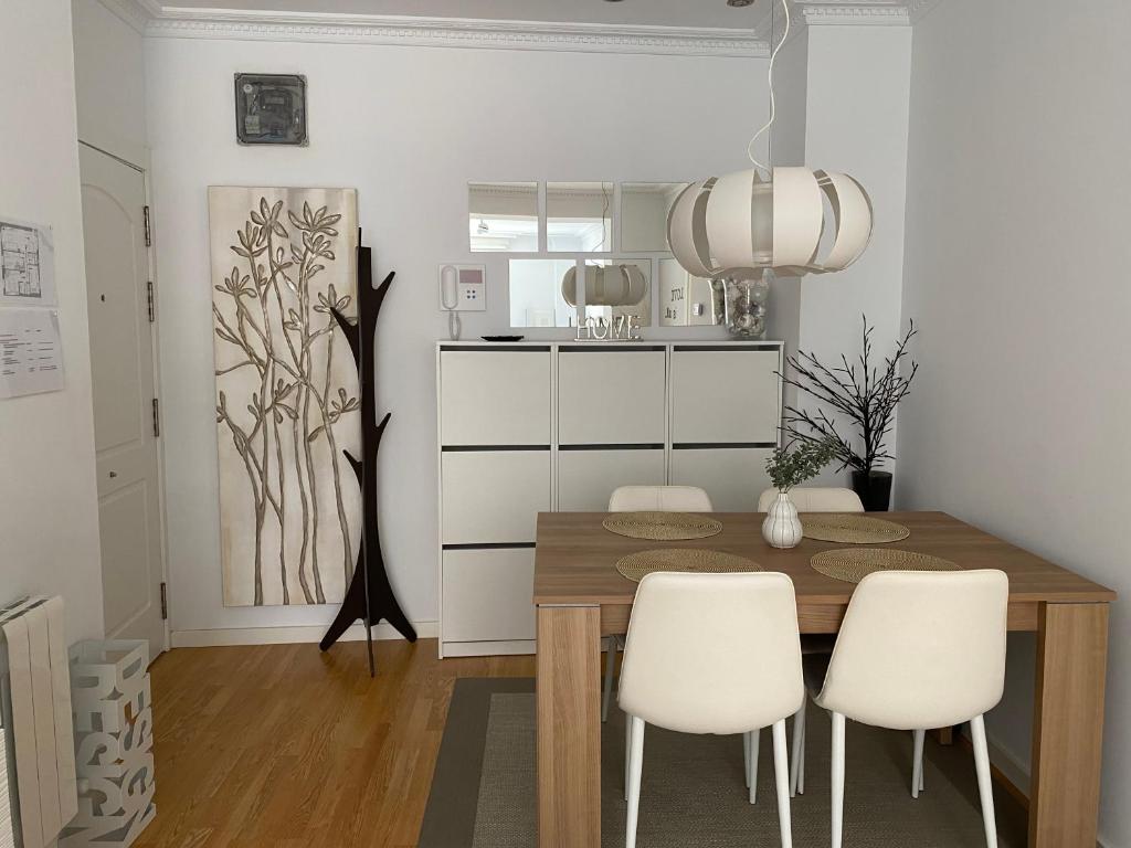 a dining room with a wooden table and white chairs at Apartamento Lea in Bilbao