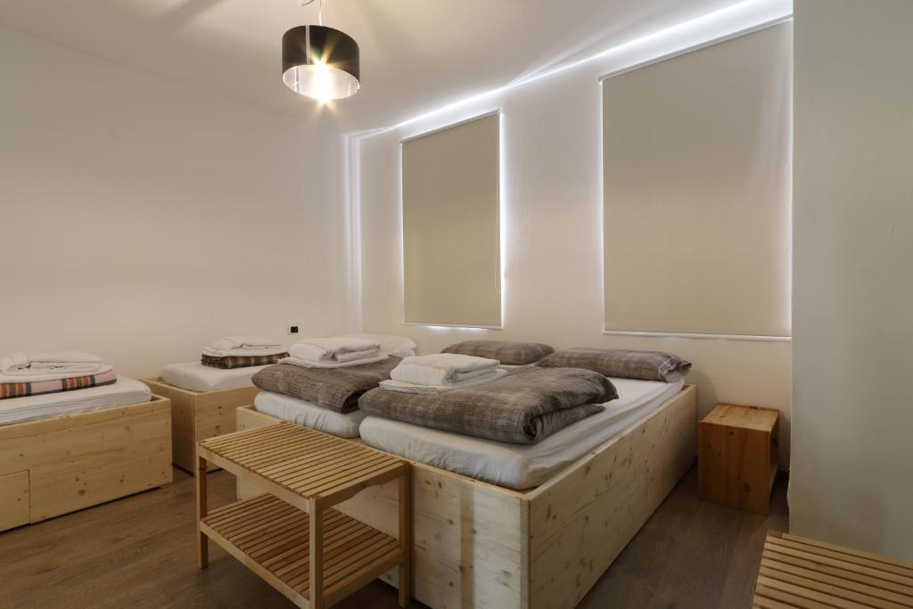 1 dormitorio con 2 camas, mesa y 2 ventanas en Bed & Wellness Fisterre, en Belluno