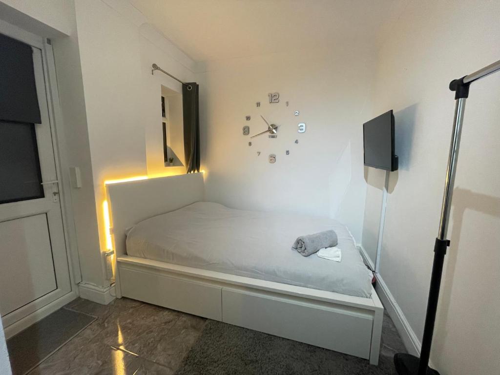 a bedroom with a bed with a clock on the wall at Greenwich Room in London