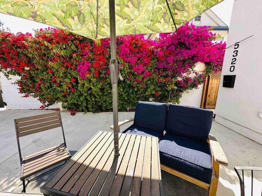 a bench and an umbrella next to a bunch of pink flowers at Secluded*NEW3BED*3BATH*Beach*SPC-X*Airforcebase in Inglewood
