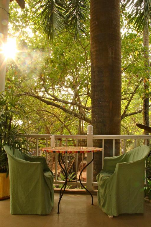 a table and two chairs on a porch with trees at Michèle's Garden in Anjuna