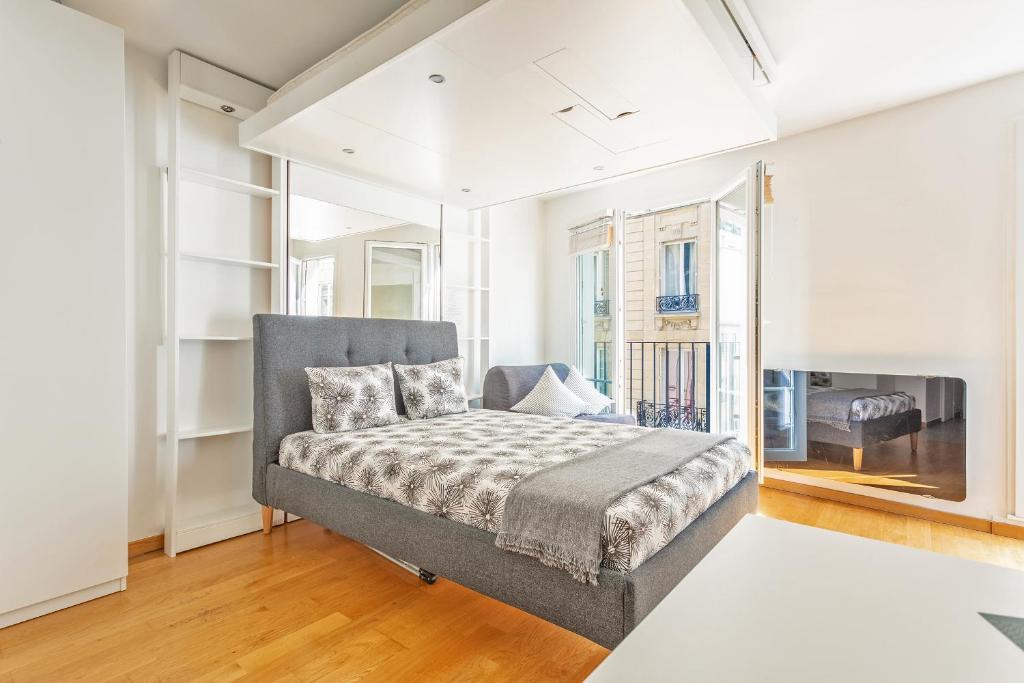 une chambre avec un lit et une grande fenêtre dans l'établissement Arc de Triomphe Luxury Place, à Paris