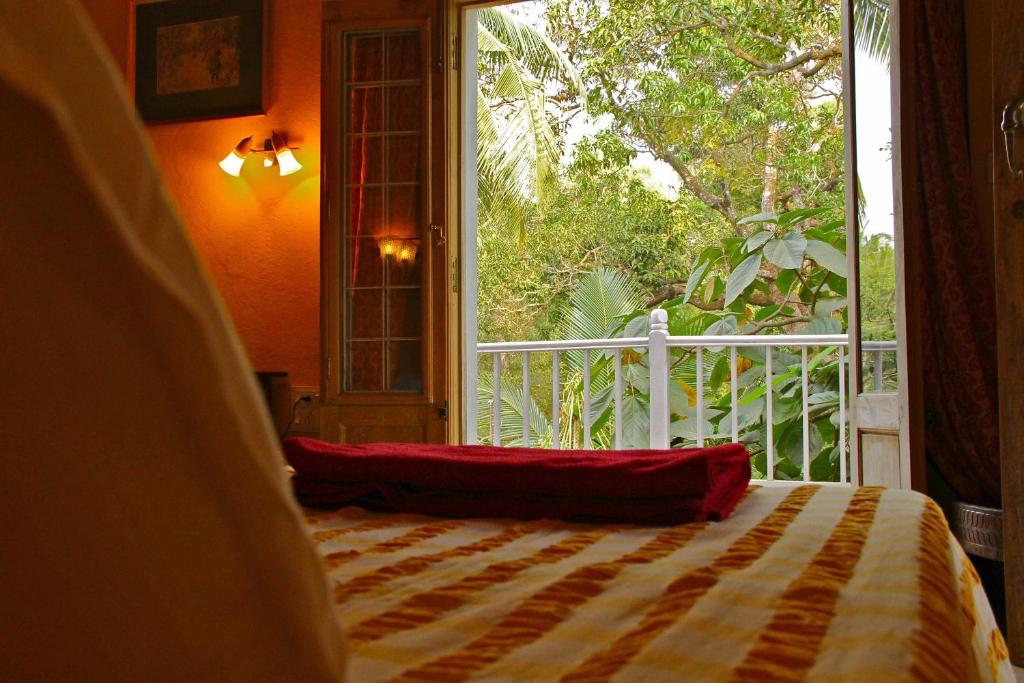 a bedroom with a bed and a large window at Michèle's Garden in Anjuna