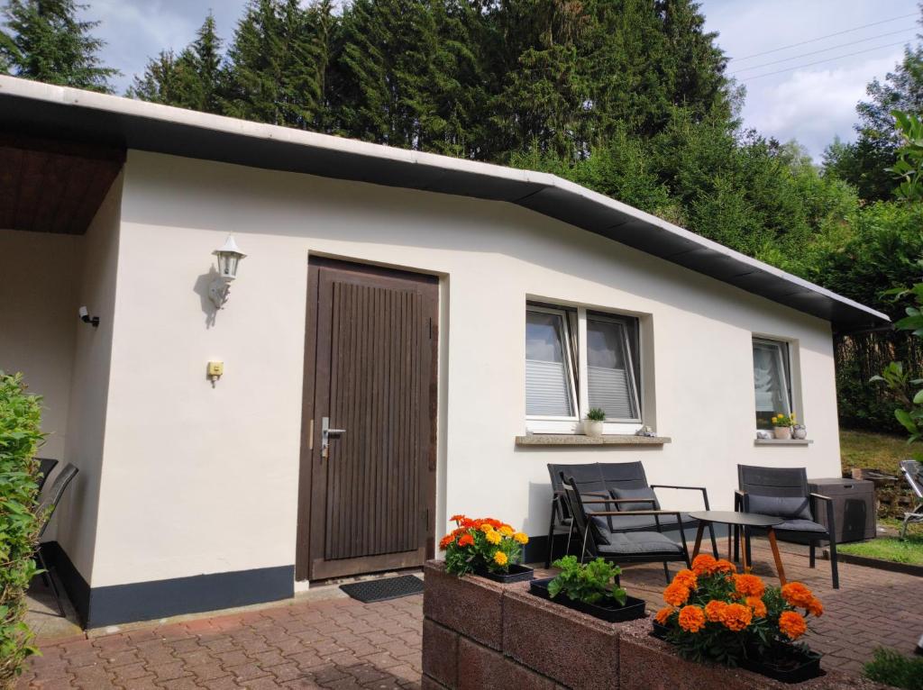 een klein wit huisje met een deur en een patio bij Ferienhaus Jung in Katzhütte