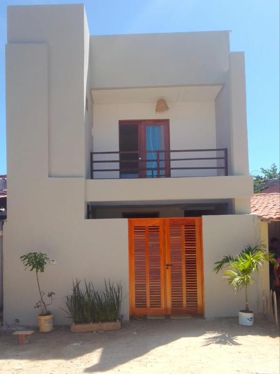 a white house with orange doors and a balcony at Suite Economica Wind Jeri in Jericoacoara
