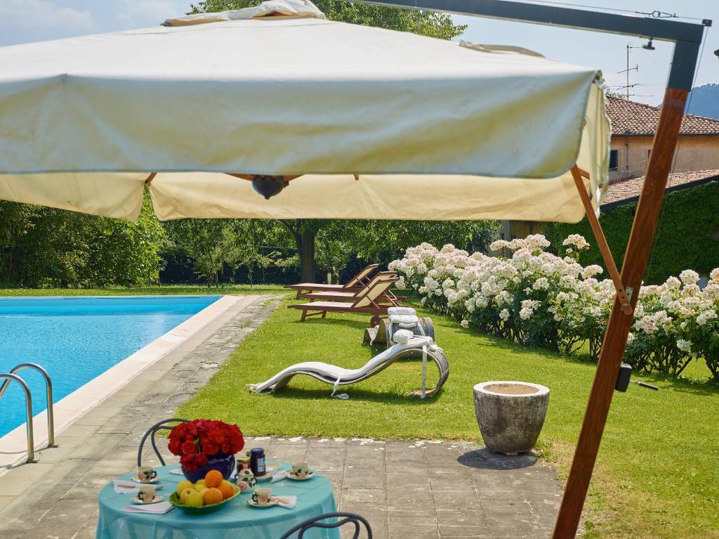 ein großer Regenschirm über einem Tisch neben einem Pool in der Unterkunft Villa Milesi in Franciacorta in Erbusco