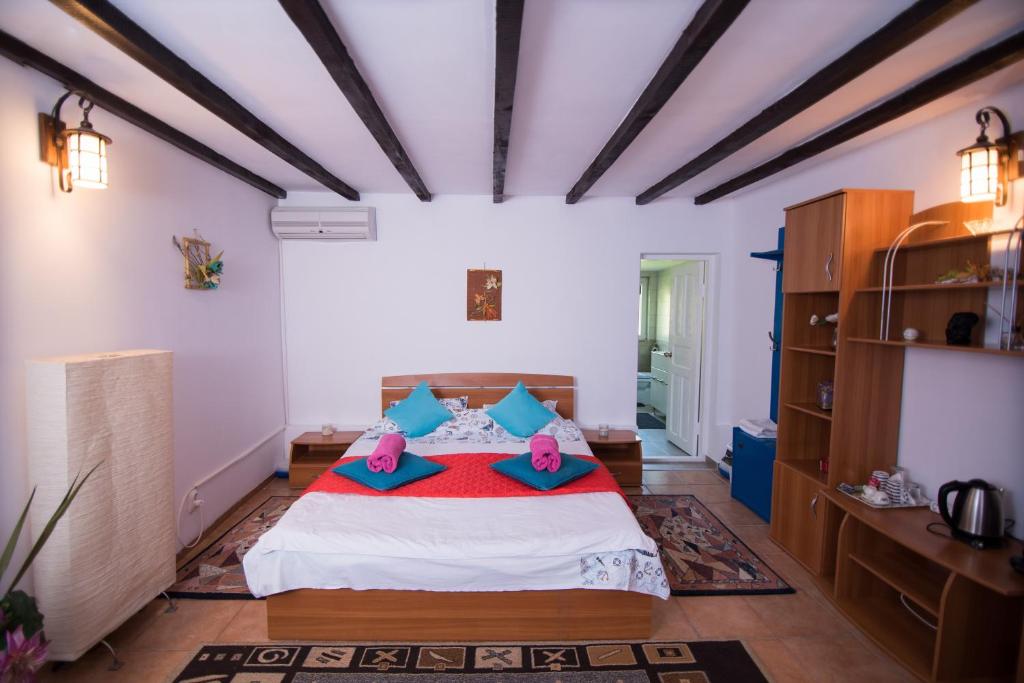 een slaapkamer met een bed met blauwe en roze kussens bij Pensiunea La Gura Portitei - Jurilovca in Jurilovca