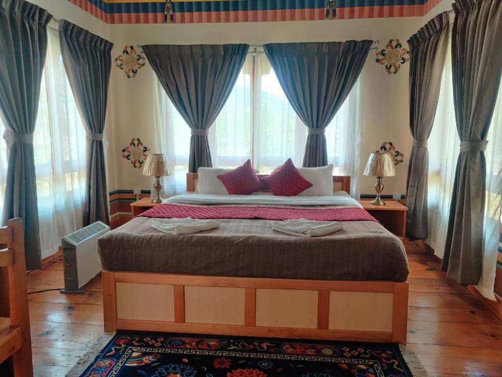 a bedroom with a large bed with blue curtains at Nirvana Lodge in Paro