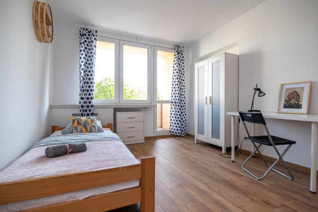 a bedroom with a bed and a desk and a window at Regem Pokoje Nowogrodzka in Warsaw