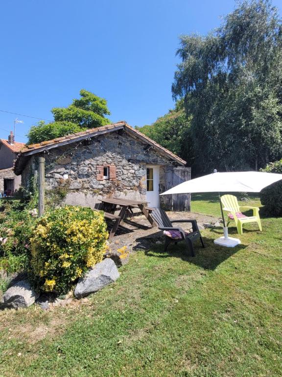 ein Haus mit einem Tisch, 2 Stühlen und einem Sonnenschirm in der Unterkunft La maisonnette in Moncoutant