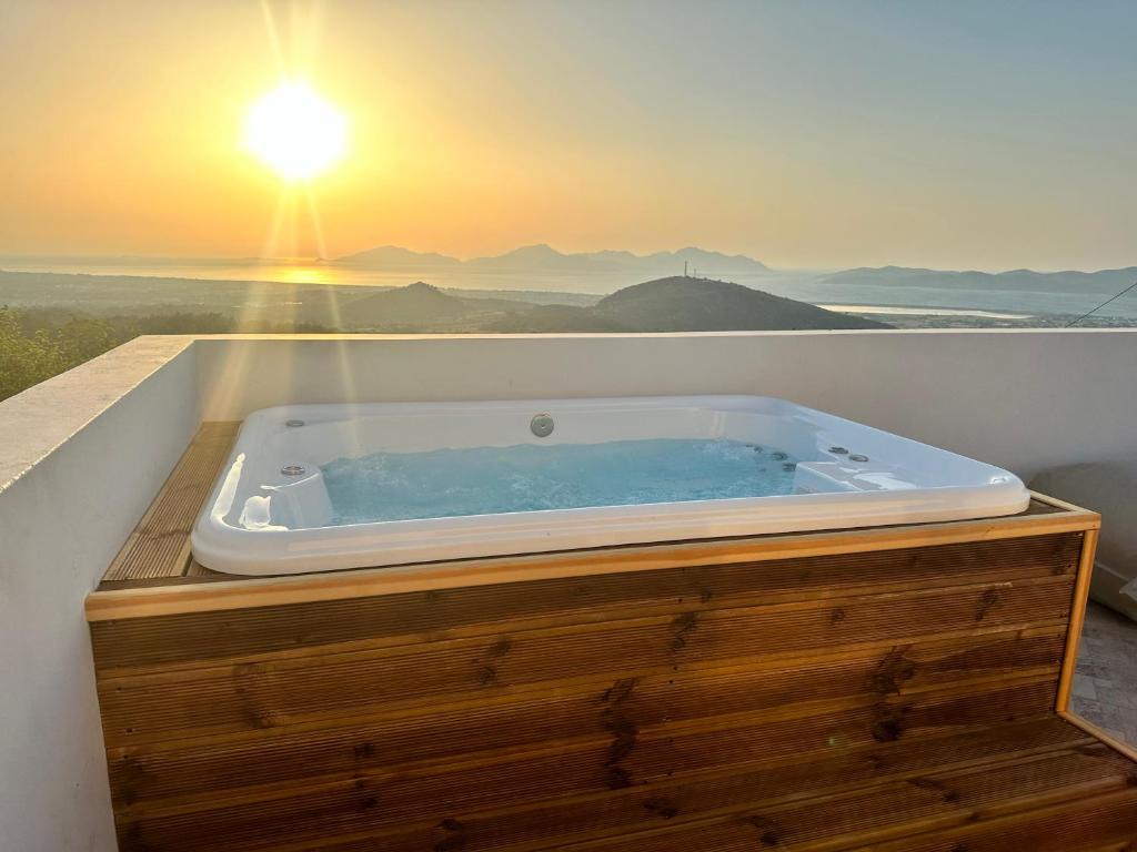 a jacuzzi tub on a balcony with the sunset at LΟFT by Casa di Somnia in Lagoúdi Zía