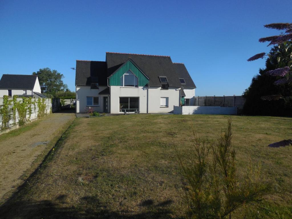ein weißes Haus mit einem grünen Dach auf einem Feld in der Unterkunft Maison de vacances au calme entre St Malo et Cancale in Saint-Méloir-des-Ondes