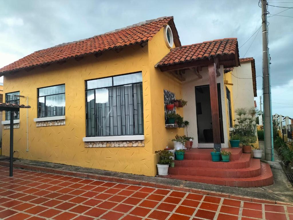 una casa amarilla con techo de baldosas rojas en CASA LA PRADERA, en Paipa