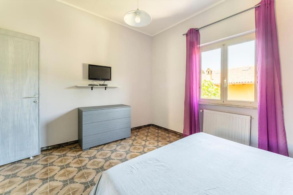 sypialnia z łóżkiem, telewizorem i fioletowymi zasłonami w obiekcie Come A Casa w mieście Ostia