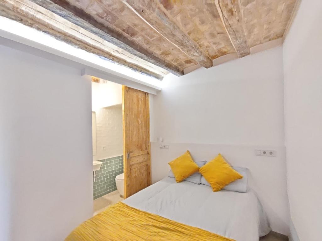 een slaapkamer met witte muren en een bed met gele kussens bij Antic Apartament in Manresa