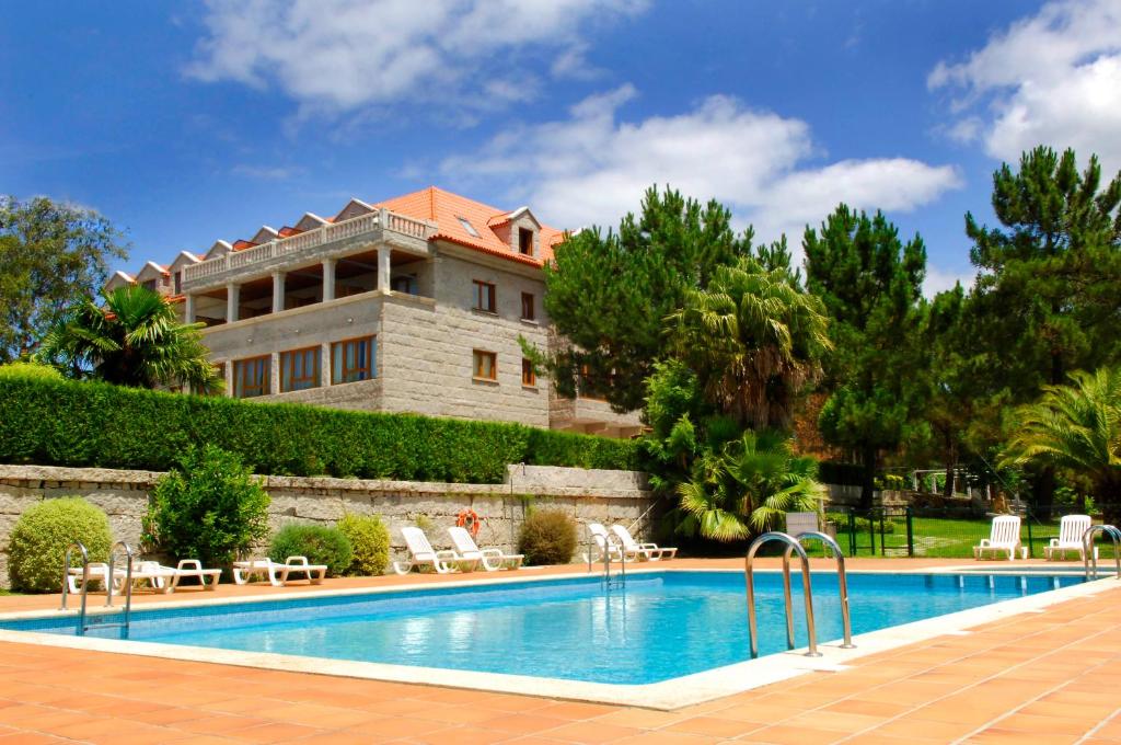 a resort with a swimming pool in front of a building at Hotel Abeiras in O Grove