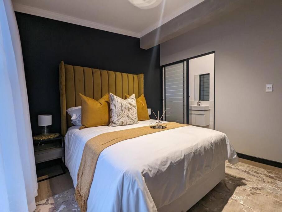 a bedroom with a large bed with yellow pillows at 1 Elizabeth Place - Beautiful self catering 2 bedroom unit next to Kyalami Racetrack with free WiFi - swimming pool gym and restaurant - Perfect for a small family in Midrand Waterfall in Midrand